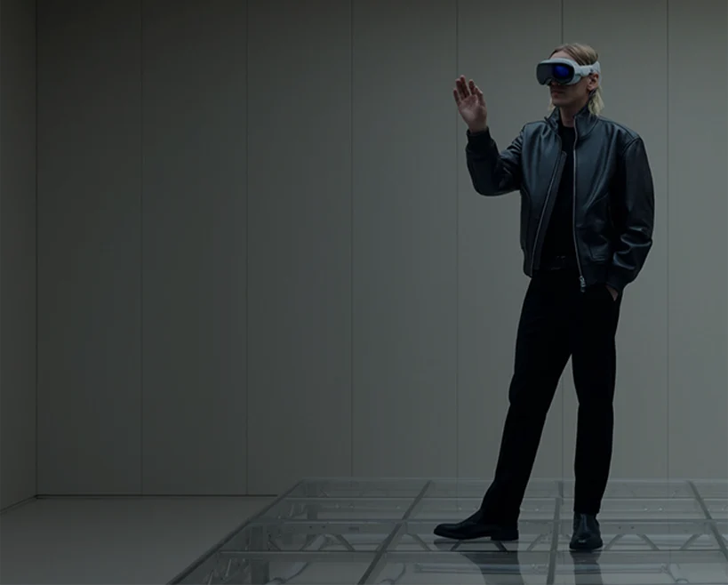 Person wearing a VR headset stands on a transparent platform in a minimalist room and gestures in the virtual environment. (photo)
